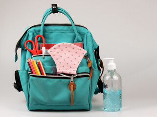COVID-19 prevention , back  to school  and new normal  concept.Front view of  pink polka dots fabric mask , sanitizer gel and  backpack with school supplies