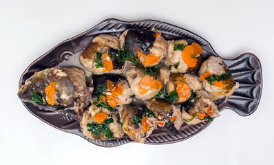 Stuffed fish carp on a brown ceramic dish in the shape of a fish close up on a white background