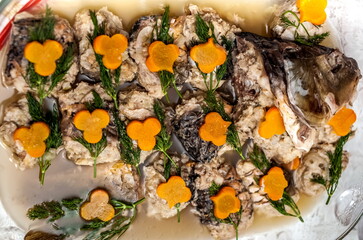Fototapeta na wymiar Stuffed fish carp, decorated with sprigs of dill and curly slices of carrots close-up