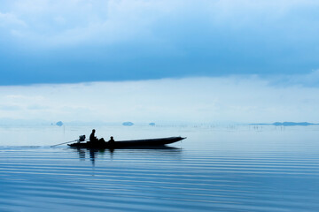 Obraz premium Silhouettes of fishing boat on the lake in blue hour