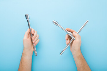 Young adult man hands holding metal wrench on light blue table background. Pastel color. Closeup. Point of view shot. Top down view.