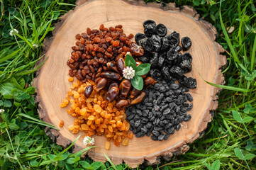 Assorted raisins, dates and prunes on a wooden background on the grass. Photo for the catalog. Assortment of dried fruits