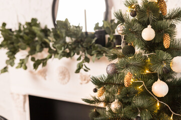 Close up of holidays location with words Christmas tree, mirror on white fireplace candles and garlands