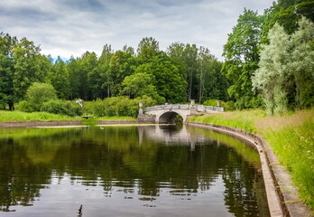 Summer landscape in a city Park with trees, stone bridge and sky with clouds