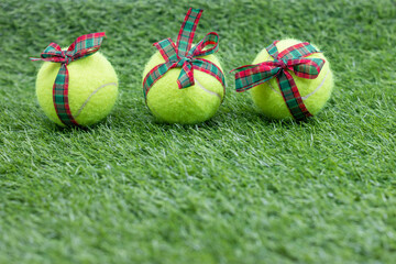 Tennis Christmas with tennis ball with Christmas ribbon on green grass