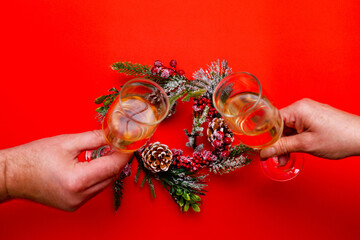Top view Two male and female hands holds glasses of champagne, a wreath on a red background