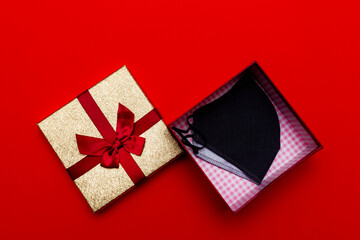 Top view Christmas,New year gift box flat lay with a face mask on a red background