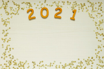 Happy New year 2021 celebration. Gold wooden numbers 2021 and gold confetti on yellow fantasy background. Flat lay with space for text