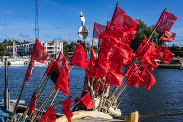 Fototapeta na wymiar Red flag on a fish boat in port on the Vistula Lagoon in Katy Rybackie village located on the Vistula Spit between lagoon and Baltic Sea in Poland