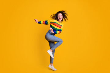 Fototapeta na wymiar Full length photo of funny jumping woman dressed casual colorful sweatshirt dancing looking empty space isolated yellow color background