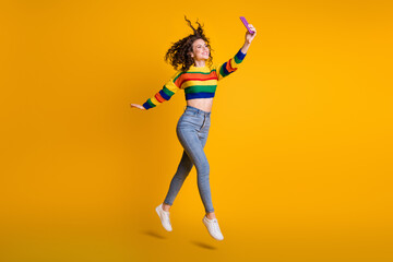 Full length photo of shiny jumping woman dressed casual colorful sweatshirt making selfie isolated yellow color background