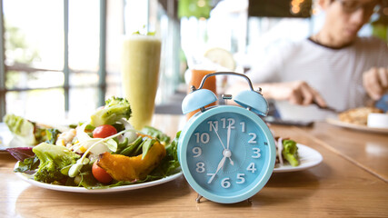 Selective focus of blue clock and breakfast time, alarm clock ntermittent fasting as a healthy and...