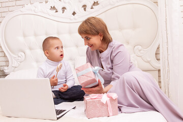 A boy with Down syndrome and a disability sits with his mother on the couch, online video greetings...