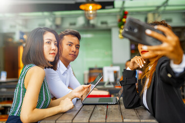 Business meeting outdoor. Two asian women and one asian man seated at a restaturant table
