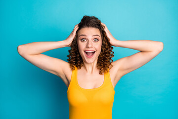 Photo of pretty excited student girl hands head open mouth amazed look camera wear yellow singlet isolated blue color background