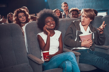 Woman smiling and talking on the phone in cinema.