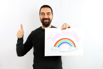 Young man with beard, smiling, holds a sign in his hand with the inscription in Spanish 