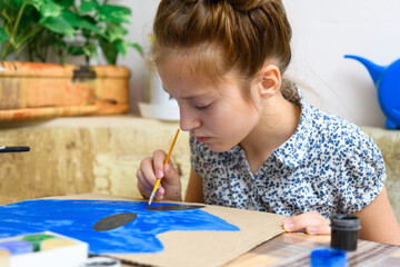 a girl drawing blue gouache cardboard, artistic creation at home, makes creative artwork