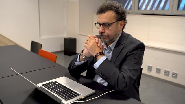 Stressed frustrated businessman wearing glasses at work. Exhausted tensed worker , emotional stress concept feeling pain sitting at office desk with laptop.