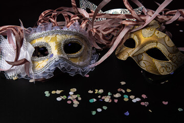 Venetian masks and carnival props from Brazil arranged on black surface, selective focus.