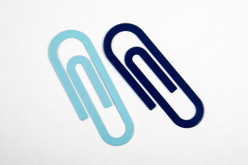 Two blue paper clips on a white background. Stationery and office supplies
