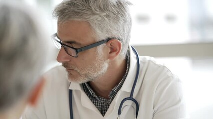 Mature doctor in office listening to patient - Powered by Adobe