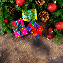 Christmas background with gift boxes Packed in different colors on a brown wooden table. Christmas or new year gifts under the fir branches. The view from the top. Copyspace