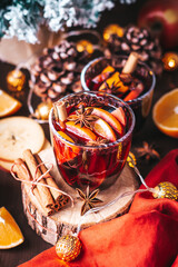Mulled wine on table with Christmas lights and red napkin, cozy winter still life. Winter lifestyle at home, winter drink closeup, warm atmosphere