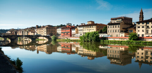 Fototapeta na wymiar Panoramic view of the city of Florence on the banks of the Arno river with the reflection of the colored houses in the water.