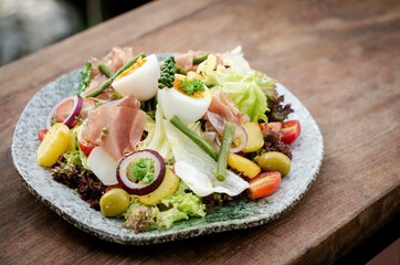 nicoise style healthy organic salad with egg and ham outdoors