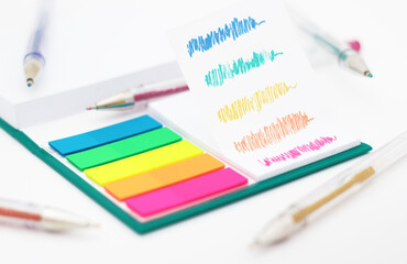Various colored pencils, paper, notes on white background.