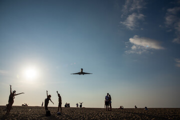 Fototapeta na wymiar Silhouette of people on sand beach with the plane over the head
