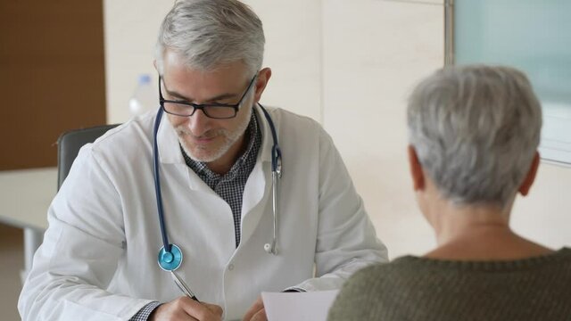 Mature doctor in office listening to patient