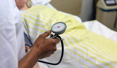 Dunkelhäutige Pflegerin misst den Blutdruck einer bettlägerigen Patientin  – Selektiver Fokus 