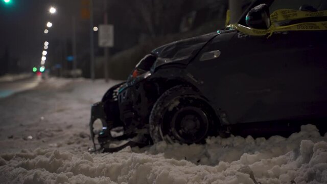 Aftermath of MVA motor vehicle accident on snowy winter night with traffic light and street lights in background in urban setting