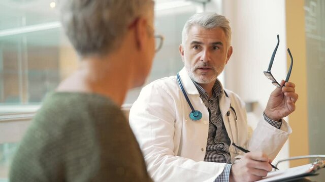Mature doctor in office listening to patient