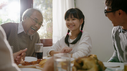 Happy asian family enjoy breakfast together. Cheerful parents, grandfather and cute daughter enjoy breakfast together on dining table at home. wonderful moment family