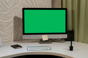 A computer with a green screen stands on the table.