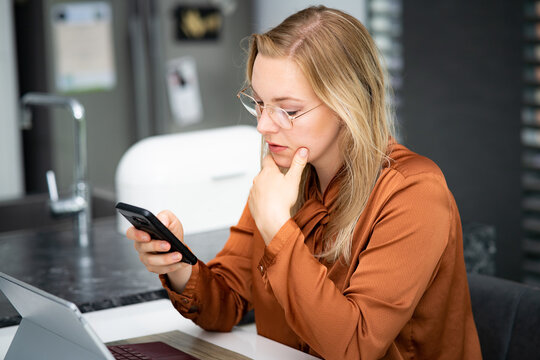 Private Kontakte w&auml;hrend der Arbeitszeit - junge Angestellte checkt im B&uuml;ro Nachrichten auf dem Handy - Symbolfoto
