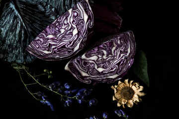 red cabbage on a dining table covered with a black tablecloth. still life with cabbage and flowers...