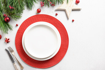 Christmas holiday table setting with white and red holiday decorations on white table.