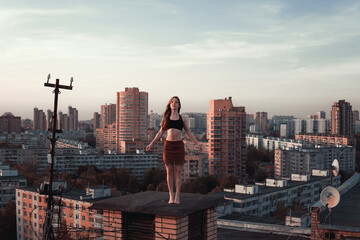 Girl in a tank top and a skirt barefoot on the roof