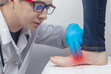 An orthopedic surgeon examines a woman's leg. Foot pain, tendon sprains, inflammation, flat feet,...