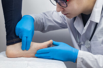 An orthopedic surgeon examines a woman's leg. Foot pain, tendon sprains, inflammation, flat feet,...