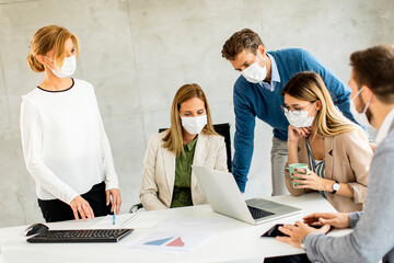 Team of business people working on project with facial masks as a virus protection