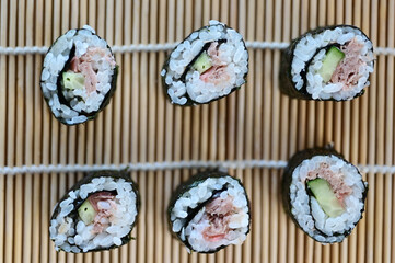 Flat lay view of group of fresh rolled sushi on bamboo sushi mat