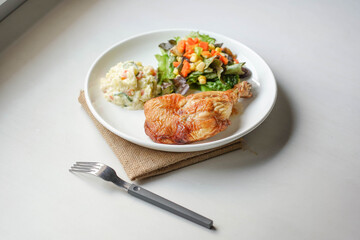 plate of delicious grilled chicken legs steak with vegetable and salad potato on white background