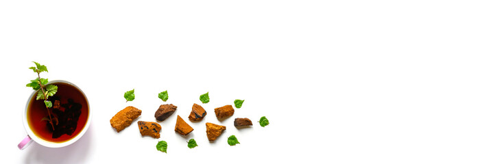 Cup of tea of birch chaga mushroom and crushed chaga fungus pieces for tea brewing isolated on a white background. banner. space for text