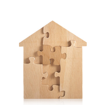 House built out of puzzle pieces on wooden background