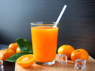 Glass of fresh orange juice with orange fruit and ice cube on wooden table for healthy drink concept.